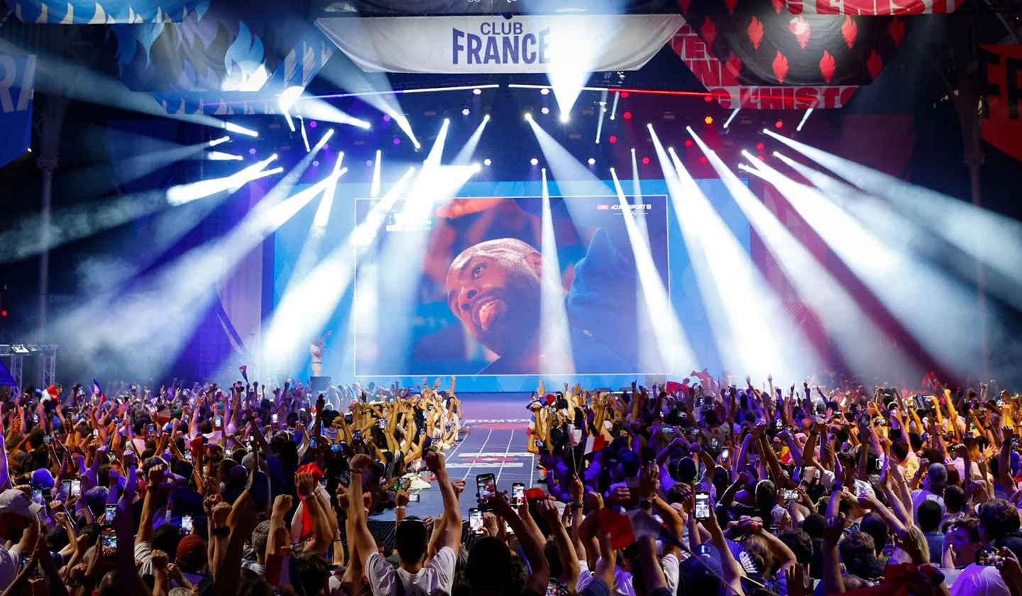 Grande público celebra diante do palco iluminado do Club France nos Jogos de Paris 2024